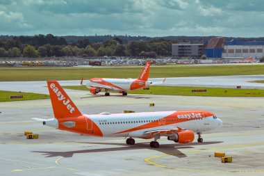 Londra, İngiltere, İngiltere - 1 Ağustos 2023: Airbus A320 yolcu uçağı, Londra Gatwick havaalanından kalkmak için G-EJCD plakalı uçakla kalkışa hazırlanıyor. Arka planda başka bir kolay jet uçağı var..