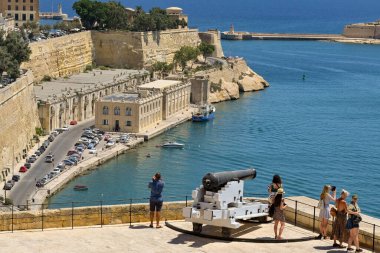 Valletta, Malta - 8 Haziran 2023: Şehrin antik tahkimatları üzerinde eski bir top ile birlikte ziyaretçiler