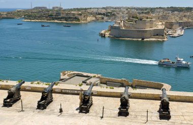 Valletta, Malta - 8 Haziran 2023: Geleneksel üniformalı solider, şehrin antik tahkimatlarının tepesindeki selamlama bataryasındaki eski topların yanında duruyor