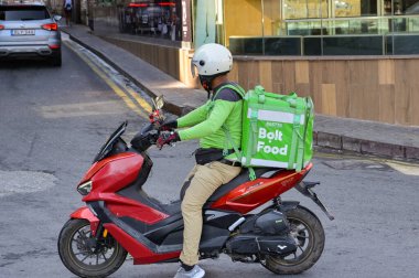 St Julians, Malta - 4 Ağustos 2023: Arkasında Bolt Food dağıtım servisi için izole edilmiş bir konteynır bulunan motosiklet kullanan kişi