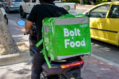 Gozo, Malta - 5 Ağustos 2023: Arkada Bolt Food dağıtım servisi için izole edilmiş bir konteynır taşıyan motosiklet kullanan kişi