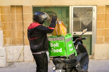 St. Julians, Malta - 8 Ağustos 2023: Bolt Gıda dağıtım servisi için izole edilmiş bir konteynıra sipariş yükleyen teslimatçı