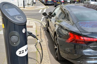 London, England, UK - 22 August 2023: Electric car plugged into a rapid battery recharging point on a street in central London clipart