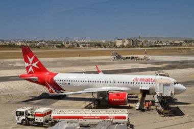 Luqa, Malta - 7 Ağustos 2023: Air Malta Airbus A320 Neo uçağı adanın uluslararası havaalanında. Ön planda bir yakıt kamyonu var.