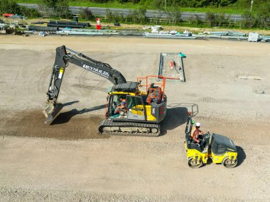 Pontyclun, Galler - 7 Eylül 2023: Bir kazıcı ve paten makinesinin insansız hava aracı görüntüsü Güney Galler 'de yeni bir süpermarket gelişimi için otoparkı hazırlıyor.