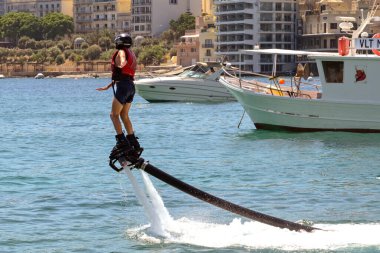 St Julians, Malta - 2 Ağustos 2023: St Julian Körfezi 'nde su püskürtme botları kullanmayı öğrenen genç kişi