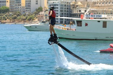 St Julians, Malta - 2 Ağustos 2023: St Julian Körfezi 'nde su püskürtme botları kullanmayı öğrenen genç kişi
