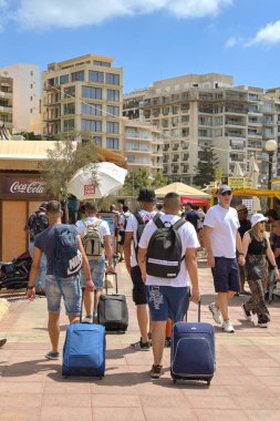 Sliema, Malta - 6 Ağustos 2023: Gençler Sliema 'daki gezinti güvertesi boyunca bavullarını çekiyorlar.