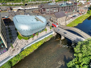Pontypridd, Galler - 12 Eylül 2023: Şekerleme Nehri 'nin yanındaki yeni halk kütüphanesinin insansız hava aracı görüntüsü. Sağdaki tarihi Eski Köprü.