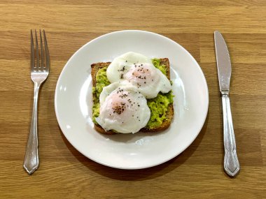 İki haşlanmış yumurta ve kahverengi tost üzerine karabiber. Masanın yanında çatal ve bıçakla. Kimse yok..