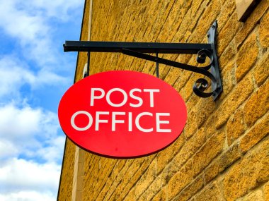 Broadway, Worcestershire, UK - 5 November 2023: Sign on the outside wall of the village post office in Broadway. The wall is made of yellow Cotswold stone. clipart