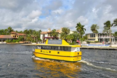 Fort Lauderdale, Florida, ABD - 2 Aralık 2023: Şehrin su yollarından birinde lüks evlerin önünden geçen su taksisi