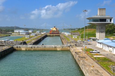 Kolon, Panama - 23 Ocak 2024: Agua Clara Panama Kanalı 'ndaki kontrol kulesine kilitlendi. Arka planda bir konteyner gemisi ve Atlantik köprüsü var.