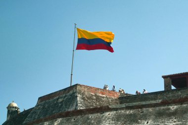 Cartagena, Bolivar, Kolombiya - 24 Ocak 2024: Tarihi Castillo San Felipe de Barajas şatosunun tepesinde Kolombiya bayrağı altında ziyaretçiler