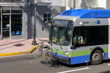 Miami, Florida, ABD - 1 Aralık 2023: Bisikletli kamu servis otobüsü şehrin güney sahil bölgesinde bir sokakta sürüyor