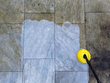 Basınç jeti yıkama makinesi bahçe verandasında porselen döşemeleri temizlemek için kullanılıyor. Temizlikten önce ve sonra farkı gösteriyor.