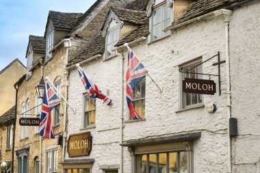 Tetbury, Gloucestershire, England, UK - 13 April 2024: Union Jack flags above shops in the town centre of the historic rural town of Tetbury. clipart