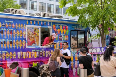 Washington DC, ABD - 3 Mayıs 2024: İnsanlar Washington DC 'nin ana yollarından birine park etmiş gezici bir dondurma kamyonundan dondurma satın alıyorlar