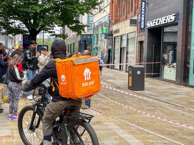Manchester, İngiltere, İngiltere - 31 Mayıs 2024: Just Eat için şehir merkezinde bisikletle teslimatçı