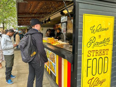 Manchester, İngiltere, İngiltere - 31 Mayıs 2024: İnsanlar şehir merkezindeki Manchester Piccadilly sokak yiyecek köyündeki bir tezgahtan sokak yiyeceği satın alıyorlar