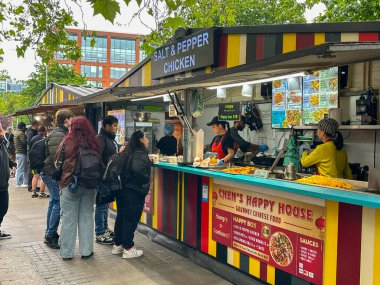 Manchester, İngiltere, İngiltere - 31 Mayıs 2024: İnsanlar şehir merkezindeki Manchester Piccadilly sokak yiyecek köyündeki bir tezgahtan sokak yiyeceği satın alıyorlar