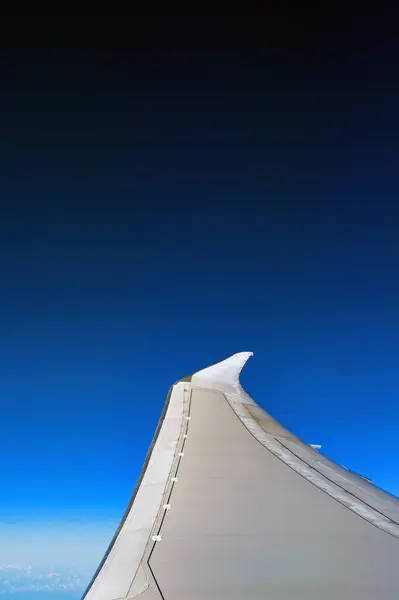 stock image Wing of a modern passenger jet in flight isolated against a deep blue sky. No people, Copy space. Travel concept. 