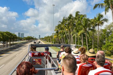 Miami, Florida, ABD - 3 Aralık 2023: Miami şehir merkezi yakınlarındaki bir otoyolda çift katlı turist gezisi otobüsünün üst güvertesindeki insanlar