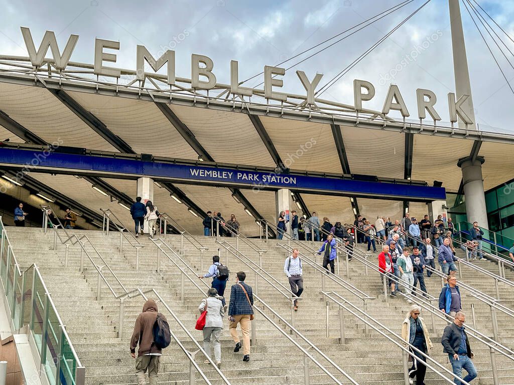 London, England, UK - 3 July 2024: People walking down steps after arriving at Wembley Park London Underground railway statuion