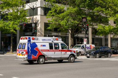 Washington DC, ABD - 2 Mayıs 2024: AMR tarafından bir şehir caddesinde acil durum ışıkları yanıp sönen bir ambulans