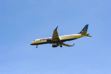 Alexandria, Virginia, USA - 1 May 2024: Embraer E190 jet (registration N283JB) operated by JetBlue in flight against a deep blue sky. clipart