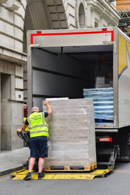 Londra, İngiltere, İngiltere - 27 Haziran 2023: Londra şehir merkezinde bir yük arabası kullanarak bir kamyon dolusu malını boşaltan kamyon şoförü.