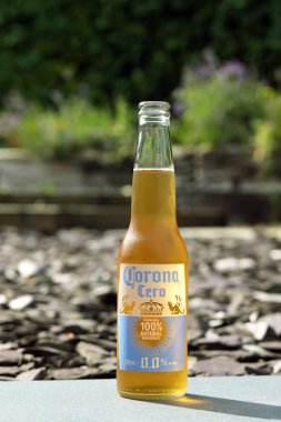 Cardiff, Wales - 30 Temmuz 2024: Bahçe duvarında soğutulmuş Corona sıfır alkollü bira şişesi açıldı. İnsan yok. Alkolden kaçınma kavramı.