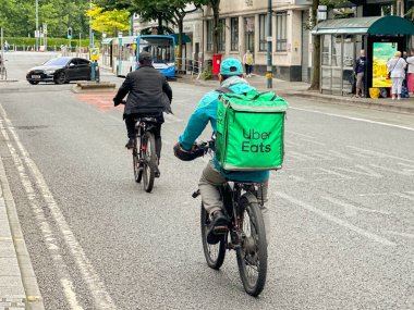 Cardiff, Galler - 24 Temmuz 2024: Cardiff City Entre 'de bir sokakta bisikletçi Uber Eats için paket yemek dağıtıyor
