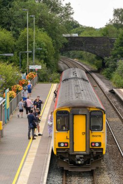 Pontyclun, Wales, UK. - 31 July 2024:  people getting on a Class 150 Sprinter diesel commuter train at the railway station in the village of Pontyclun in south Wales clipart