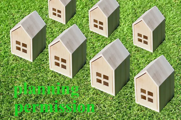 stock image Small wooden model house on a background of short green grass. Planning permission for housebuilding on green belt concept. No people. 