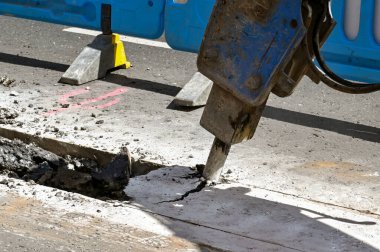 Londra, İngiltere, İngiltere - 21 Haziran 2022: Pnömatik matkap eklentisine sahip kazıcı, Londra şehir merkezindeki bir caddenin yol yüzeyini boru döşemek için kullanılıyor.