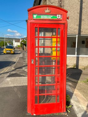 Church Village, Pontypridd, Wales, UK - 16 August 2024: AED Defibrillator to help heart attack victims stored in a converted public telephone box in Church Village in south Wales. clipart