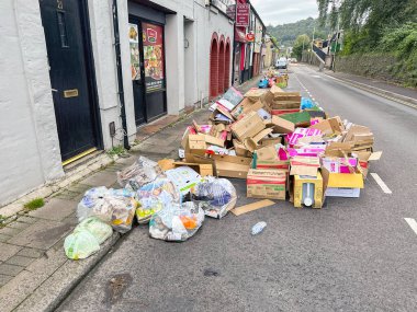 Treforest, Pontypridd, Wales - 5 September 2024: Cardboard boxes and plastic bags of sorted rubbish for recycling on the street outside a take away foor shop for the weekly collection clipart