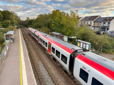 Pontyclun, Wales - 1 October 2024: People getting off and boarding a Transport for Wales Class 197 diesel commuter train stopped at the village station of Pontyclun in Rhondda Cynon Taf in south Wales. clipart