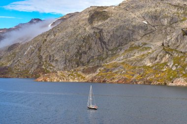 Prince Christian Sound, Greenland - 29 August 2024: Small yacht sailing up one of the fjords in Prince Christian Sound in southern Greenland clipart