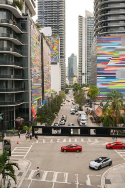 Miami, Florida, ABD - 4 Aralık 2023: Şehir merkezindeki renkli dış duvarları olan binalar arasında trafik ve yayalar.