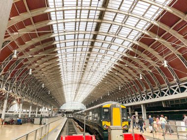 Londra, İngiltere, İngiltere - 24 Ağustos 2023: Londra şehir merkezindeki Paddington tren istasyonunun geniş açılı görüntüsü ve platformda bir banliyö treni.