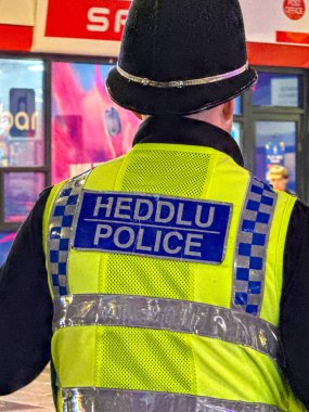 Cardiff, Wales, İngiltere - 17 Kasım 2024: Güney Galler Polisi 'nin gece şehir merkezinde görevli bir memurunun arka görüşü
