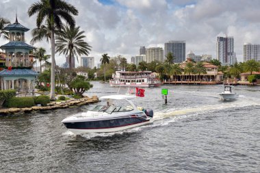 Fort Lauderdale, Florida, ABD - 2 Aralık 2024: Lüks motorlu kruvazör Fort Lauderdale 'deki su yolu üzerindeki lüks evler arasında yol alıyor.