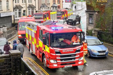 Pontypridd, Wales, UK - 24 November 2024: Fire engine of the South Wales Fire and Rescue Service with blue lights flashing on an emergency call in the town centre clipart