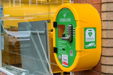 Pontypridd, Galler, İngiltere - 24 Kasım 2024: Pontypridd şehir merkezindeki bir mağazanın duvarında kilitli bir dolapta acil durum AED kalp yeniden başlatma ekipmanı