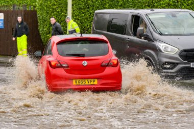 Treforest Industrial Estate, Wales, İngiltere - 24 Kasım 2024: Şiddetli yağmur sonrasında kıyılarını patlatan araçlar Şekerleme Nehri 'nden sel sularını geçiyor