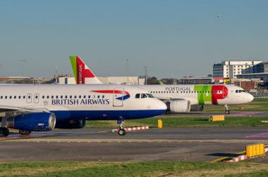 Londra, İngiltere, İngiltere - 3 Ocak 2025: British Airways Airbus A320 uçağı, Londra Heathrow havaalanından kalkmaya hazırlanan TAP Portugal Airbus A320 Neo (ruhsat CS-TVD) ile yan yana dizildi..