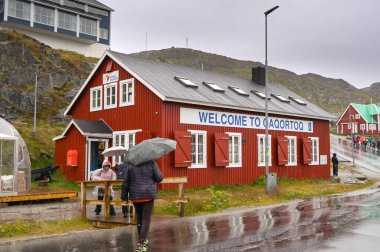 Qaqortoq, Grönland - 28 Ağustos 2024: Uzak Qaqortoq kasabasındaki bir hediyelik eşya gemisinin dışındaki bir ziyaretçi gemisinden insanlar.