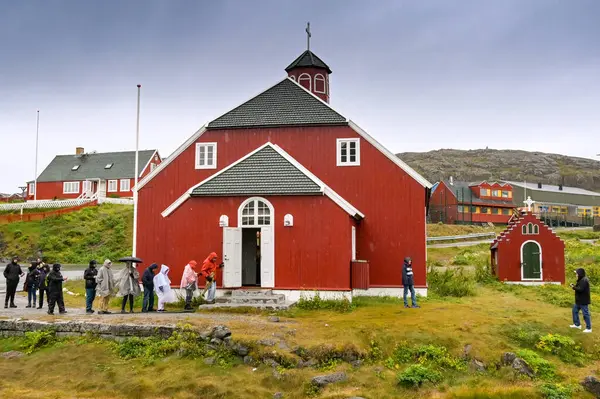 Qaqortoq, Grönland - 28 Ağustos 2024: Uzak Qaqortoq kasabasındaki tarihi Kurtarıcı Kilisesi 'ne girmek üzere olan bir yolcu gemisinden insanlar.